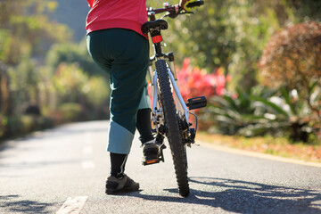 Naklejka premium Woman riding a bike on tropical park trail in spring