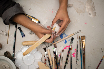 artisan hands molding a sculpture in clay and molding paste, on a table with several molding tools...