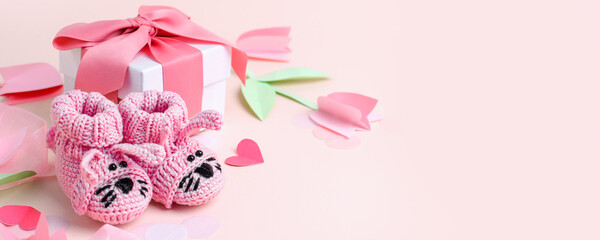 Funny rabbit pink booties on a pink background. Handmade clothes for a newborn, decorative paper...