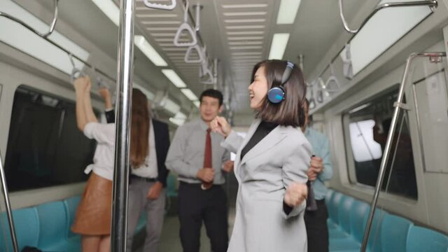 A group of businessmen having fun on the subway after work, The business man dancing happily on the train are on their way home, People of different nationalities Feel relaxed.