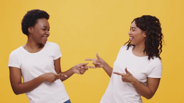 Sisters connection. Two happy african american women pointing with fingers at each other and laughing together