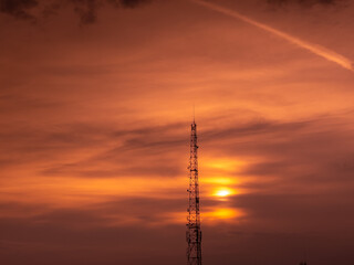 Obraz premium Communication GSM and internet antenna silhouette with dramatic sunset sky in background