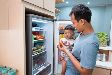 asian Young father and son open refrigerator at home looking for some food