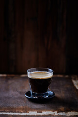 Coffee in glass cup on rustic wooden background	