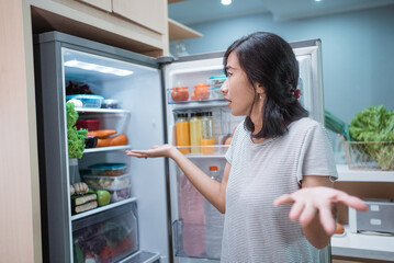 Fototapeta na wymiar dissapointed woman while opening the fridge door before cooking