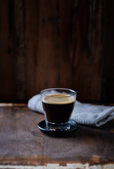 Coffee in glass cup on rustic wooden background	
