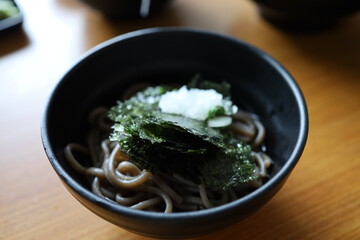 Close-up of Crispy dried seaweed, Nori chips piece of roasted seaweed sheet with noodle in a bowl on wooden table. Healthy food concept, flat lay roasted seaweed
