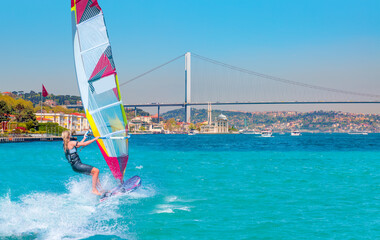 Windsurfer surfing the wind on waves - Ortakoy mosque and Bosphorus bridge - Istanbul, Turkey