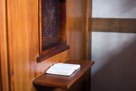 old priest inside the wooden confessional in a Christian church.