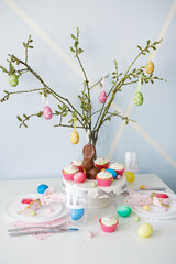 decorated table with cupcakes, colorful painted easter eggs and chocolate bunny