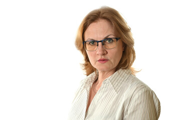 An adult attractive woman in a light blouse and glasses looks in the direction of the camera with a serious look