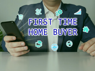  FIRST TIME HOME BUYER inscription on the screen. Modern Banker hands holding black smart phone.