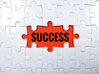 Selective focus.Word SUCCESS with magnifying glass and jigsaw puzzle on red background.Business concept.