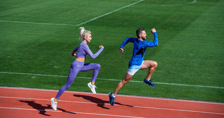 Fototapeta premium athletic couple of sprinters run on running track at stadium, success