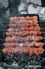 Grilling marinated meat on charcoal, outside. Shish kebab on skewers, top view. Vertical photo