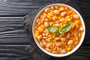 Delicious slow-stewed beans with corn, pumpkin and onions close-up in a bowl on the table....