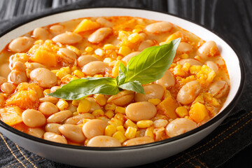 Delicious slow-stewed beans with corn, pumpkin and onions close-up in a bowl on the table. horizontal