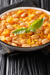 Beans stew with corn, pumpkin and onions close-up in a bowl on the table. vertical
