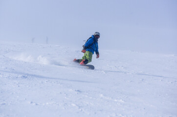 Fototapeta na wymiar A guy in a red jumpsuit eating freeride on a snowboard on a snowy slope