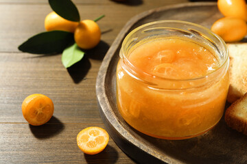 Delicious kumquat jam and fresh fruits on wooden table