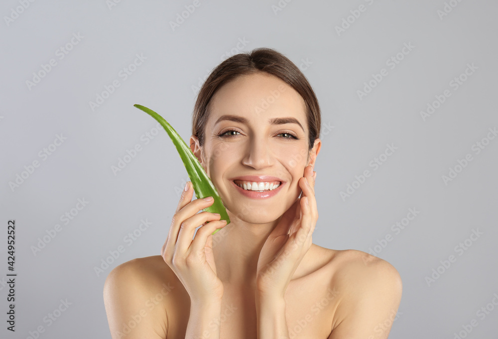 Sticker Happy young woman with aloe leaf on light grey background