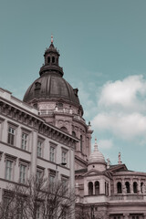 Fototapeta na wymiar Apex of St. Stephen's Basilica in Budapest, Hungary and details of historical Hungarian downtown buildings on Street Bajcsy-Zsilinszky on a spring day, european architecture, aesthetics pastel colours