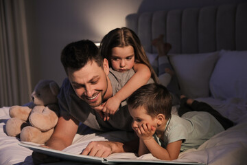 Father reading bedtime story to his children at home