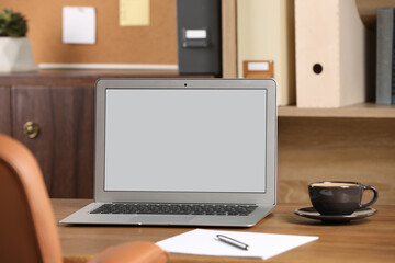 Modern laptop and cup on table in office