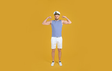 Fototapeta na wymiar Strong sailor showing biceps on yellow background