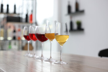 Different sorts of wine in glasses prepared for tasting on wooden table indoors