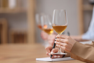 Sommeliers tasting different sorts of wine at table indoors, closeup