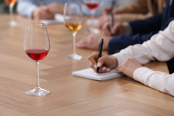 Obraz na płótnie Canvas Sommeliers making notes during wine tasting at table indoors, closeup