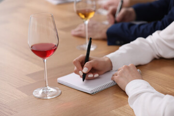 Sommeliers making notes during wine tasting at table indoors, closeup