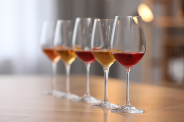 Different sorts of wine in glasses prepared for tasting on wooden table indoors
