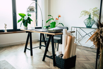 The modern stylish table in interior of the workplace with many papers, documents, and objects of the interior