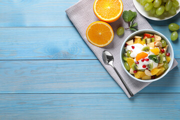 Fototapeta na wymiar Delicious fruit salad served on light blue wooden table, flat lay. Space for text