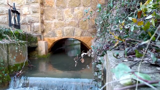 Canalization of water for irrigation in an irrigation ditch under an arch, you can see the manual sluice