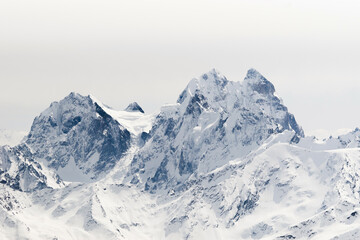 Fototapeta na wymiar Snowy Mount Ushba and Schelda on cloudy background in winter; Greater Caucasus, Russia