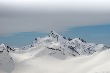 Snowy winter Greater Caucasus mountains at sunny day against blue sky and cloud. View from ski slope Elbrus, Kabardino-Balkaria, Russia