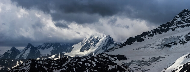 Nature background - dark stormy sky above snowy Russian Caucasus mountains in Elbrus region.