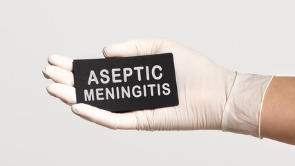 Closeup of the hand in a white sterile glove holding a card with words - Aseptic Meningitis