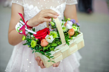 The girl holds a basket of flowers in her hands