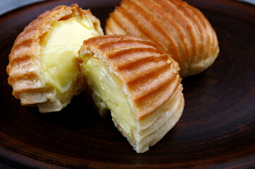 Two halves and a whole eclair on a clay plate .