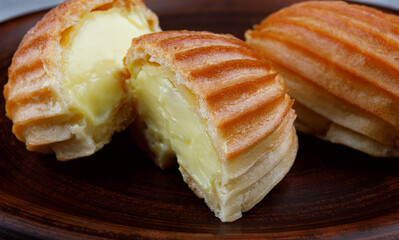 Two halves and a whole eclair on a clay plate .