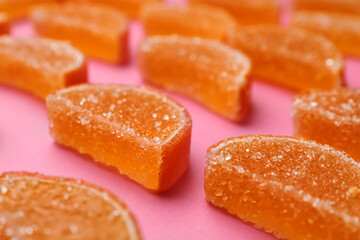 Delicious orange marmalade candies on pink background, closeup