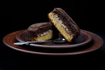 A tiramisu cake with a silver spoon on a clay plate.