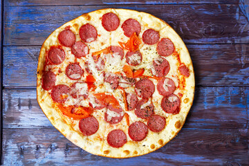 Pepperoni pizza with salami and mozzarella on wooden table.