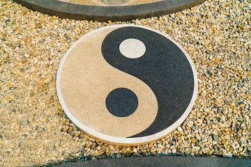 Yin Yang symbol on floor background. Black and brown Yin Yang stone sign on pebbles floor