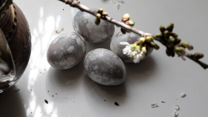 Easter eggs by the window on the table, photographed through cherry twigs