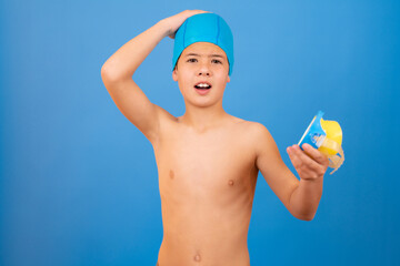 Young boy with swimmer cap and diving goggles over blue background
